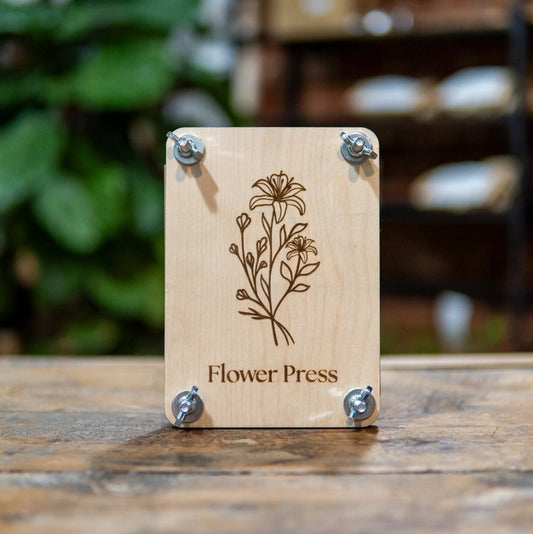 Wooden flower press with floral design and 'Flower Press' text on a wooden surface.