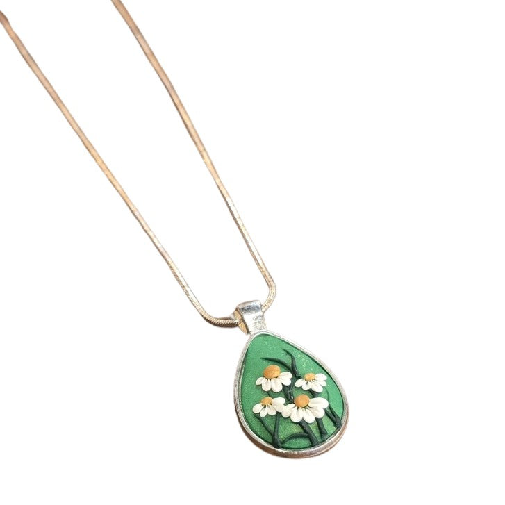 Green teardrop shaped pendant with daisies on a silver chain