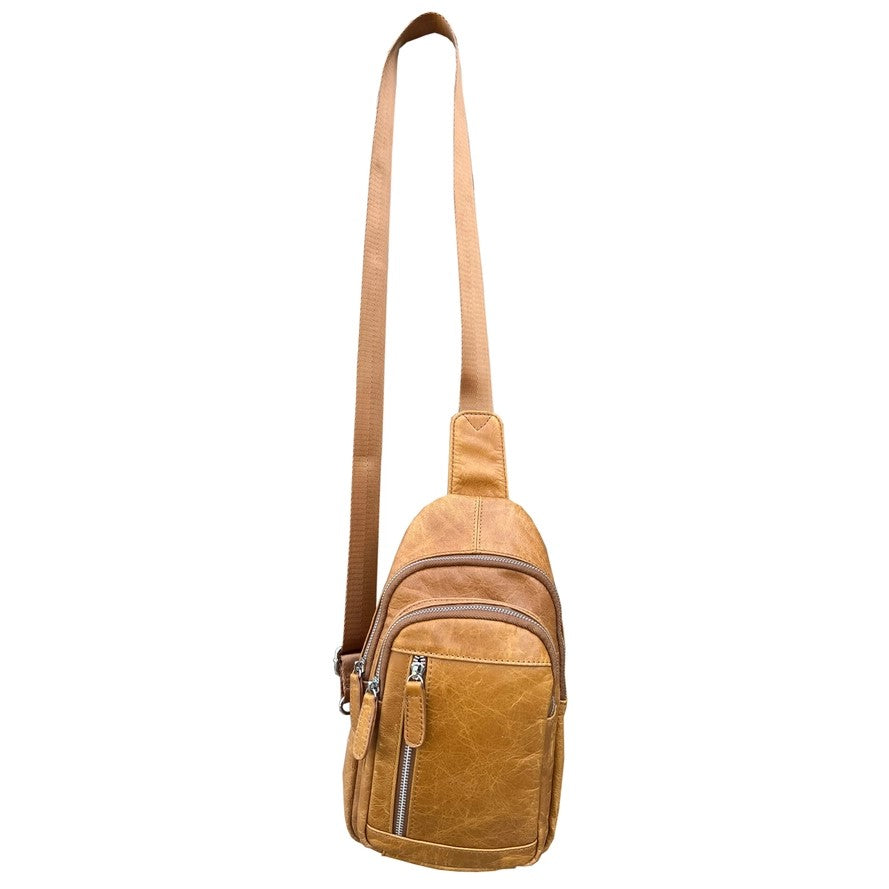 Front of a small tan leather crossbody bag with three zipper pockets on the front.