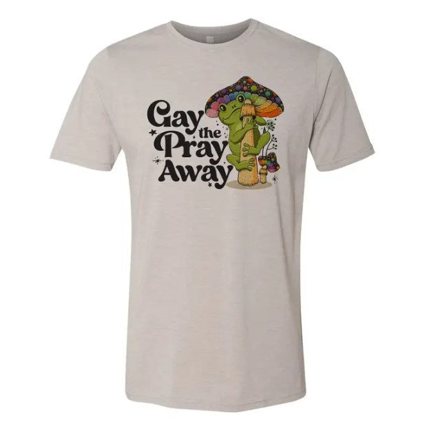 A white tee shirt featuring a groovy illustration of a smiling frog in psychedelic colors and the caption "Gay the Pray Away."