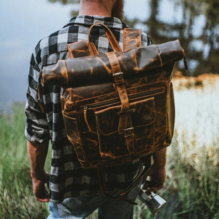 A large brown leather backpack with zipper pockets and an antique finish.