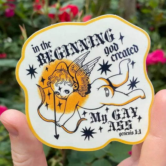 White sticker depicting a smiling cherub with fancy text that reads "In the beginning God created my gay ass"