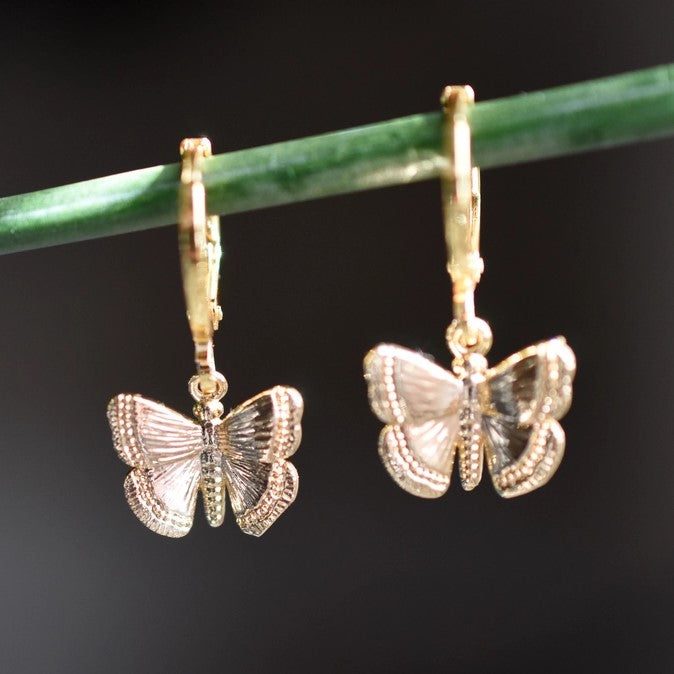 Close-up of gold butterfly charm hoop earrings