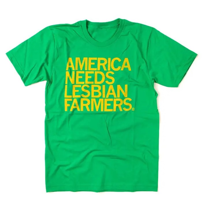 Green tee shirt with bright yellow text that reads "America Needs Lesbian Farmers."