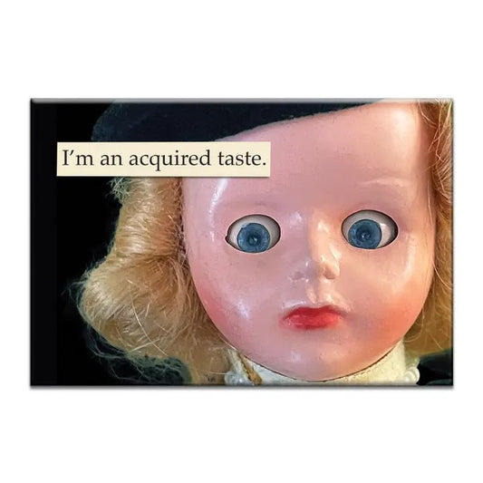 Magnet featuring a close-up photo of an antique doll's face and text that reads "I'm an acquired taste."