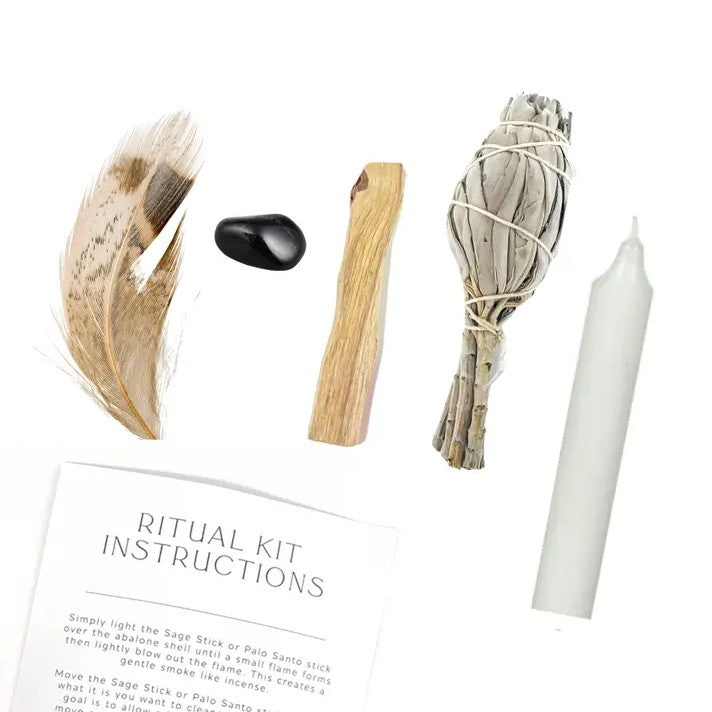 Ritual kit with sage stick, feather, stone, and candle on a white background