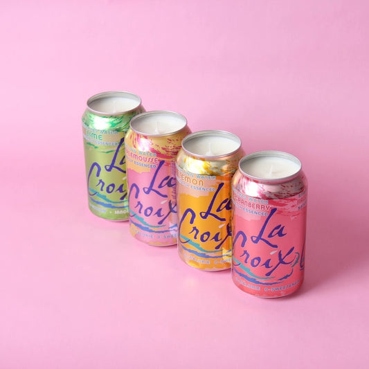Four colorful candles in La Croix cans