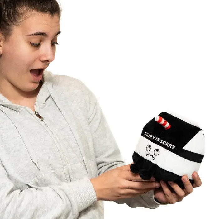 Person holding a toy shaped like a milk carton with a frowny face and embroidered words that read "dairy is scary"