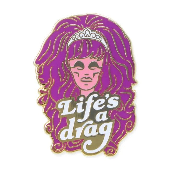Pink and purple enamel pin featuring a drag queen with large hair and text that reads "Life's a drag"