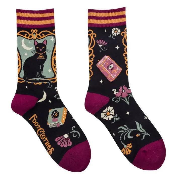 Black crew socks with black cats, flowers and books patterned on them