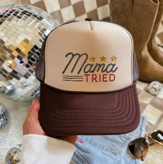 Brown and white trucker hat with the words "Mama Tried" and three gold stars on it