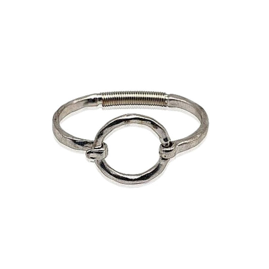 A silver-tone metal cuff bracelet with a large circular buckle-style clasp