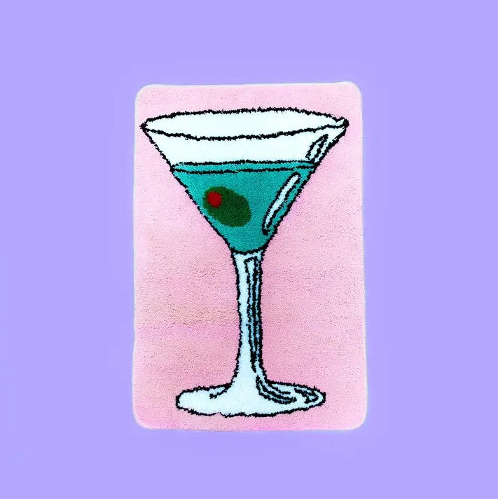 A small plush pink rug featuring a martini glass with an olive floating in it.