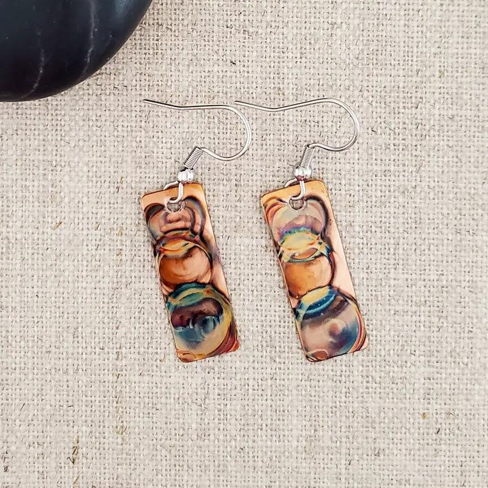 Rectangular copper earrings with iridescent circular patterns on them