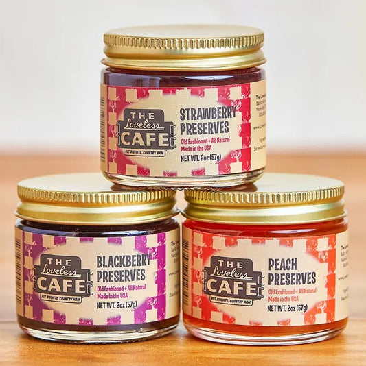 Three two ounce jars of fruit preserves on a wooden table