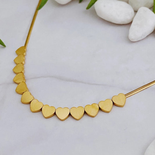 gold necklace with a row of small delicate gold hearts at the center