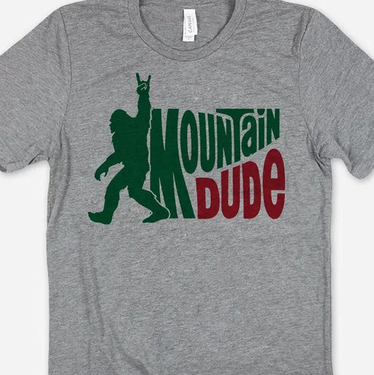 A gray tee shirt featuring a graphic silhouette of bigfoot next to the words "Mountain Dude" in the style of the Mountain Dew logo.