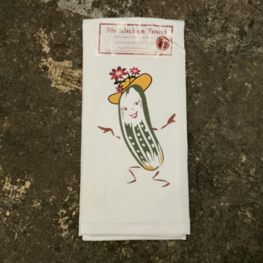 A white dish towel featuring a retro illustration of a smiling pickle with eyelashes and a flowery hat. 