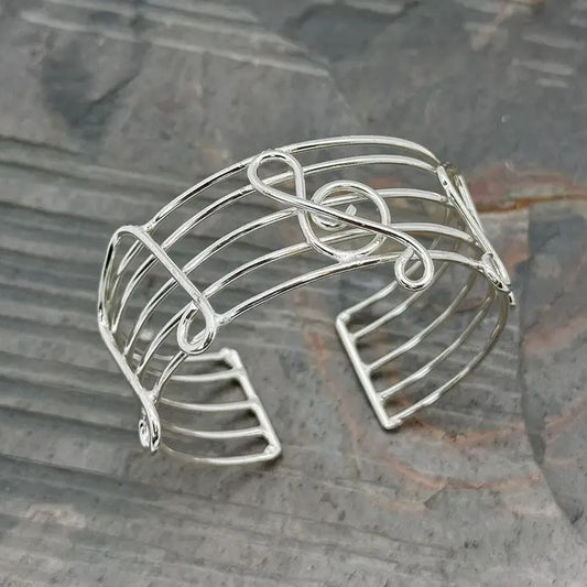 A silver wire cuff bracelet with music notes in the design