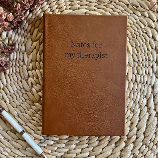 Brown leather journal with the words "Notes for my therapist" in black font on the cover