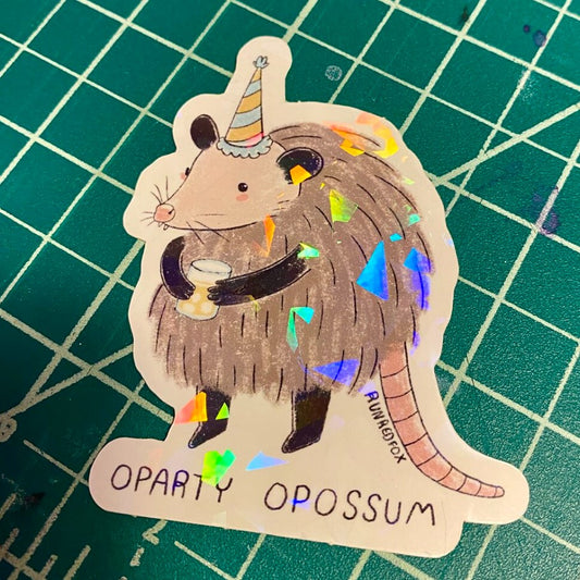 Holographic sticker of a possum wearing a party hat holding a drink