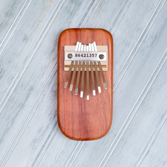 Wooden kalimba with metal tines on a light gray wooden surface