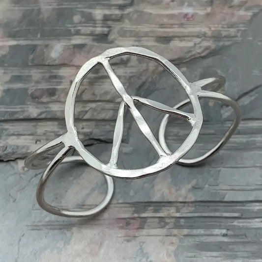 An open cuff silver bracelet with a peace sign in the center