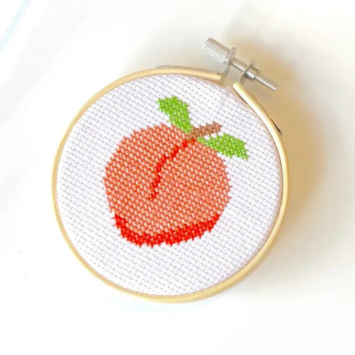 Cross stitch with an image of a peach stitched on it