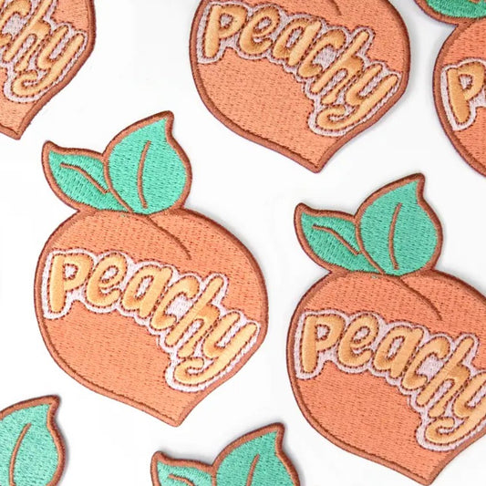 Peach shaped fabric patches with the word "peachy" embroidered