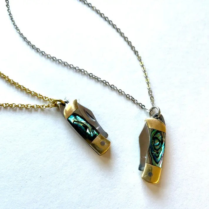 A necklace with an iridescent pendant shaped like a miniature pocket knife with 