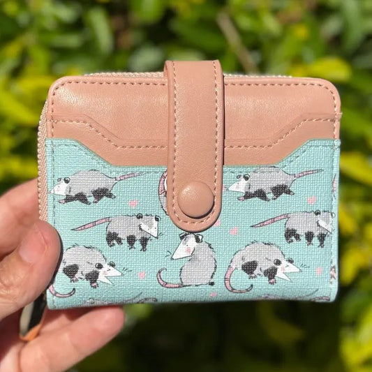 A small pink and blue wallet with cartoon possum pattern