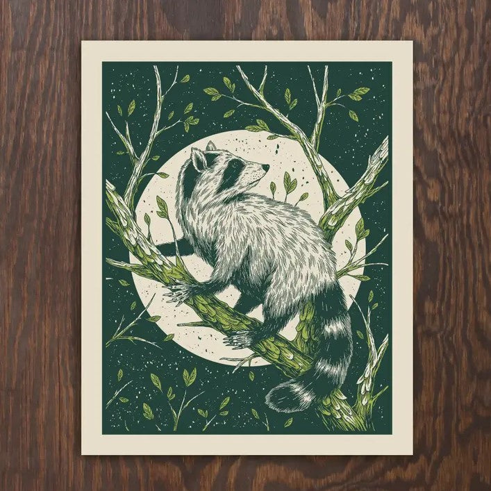 An 8x10 print of a raccoon climbing a tree branch in front of a full moon and dark green sky.