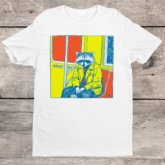 White t-shirt with a colorful graphic of a raccoon in a yellow jacket sitting on the subway 