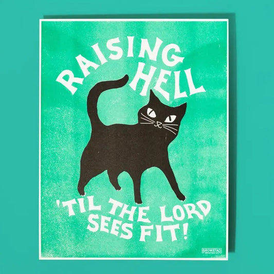 Risograph art print of a smiling black cat on a teal background and text "Raising hell 'til the lord sees fit!"