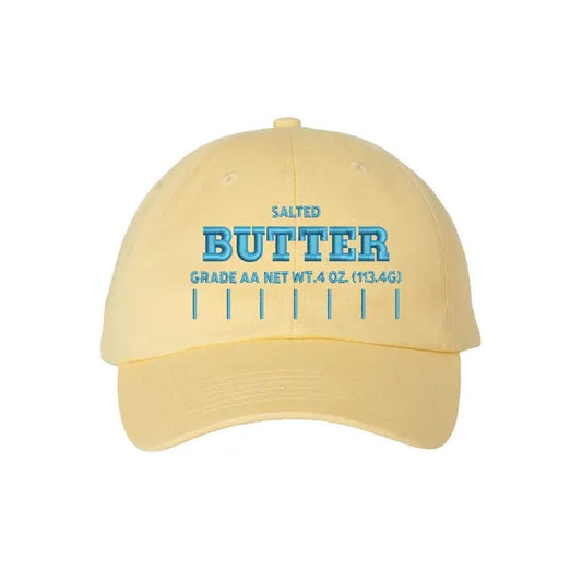 Light yellow ball cap with light blue lettering that reads "Salted butter" and measurements in the style of a butter wrapper