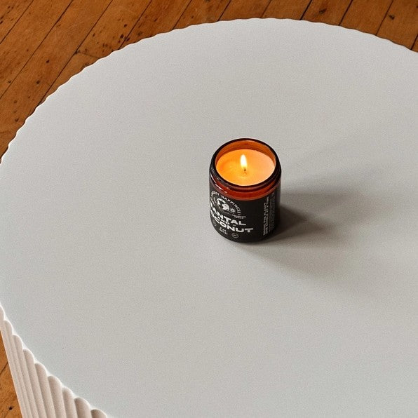 Lit candle in a brown jar on a white table