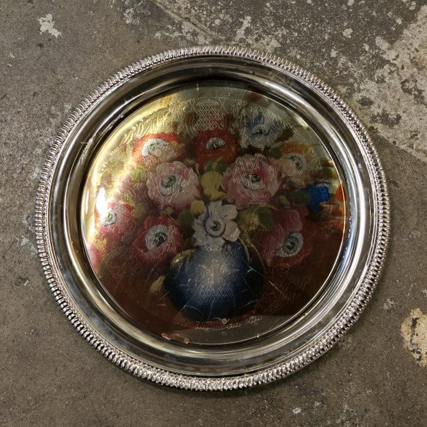 A silver metal tray with an image of a colorful bouquet with an eyeball at the center of every flower.