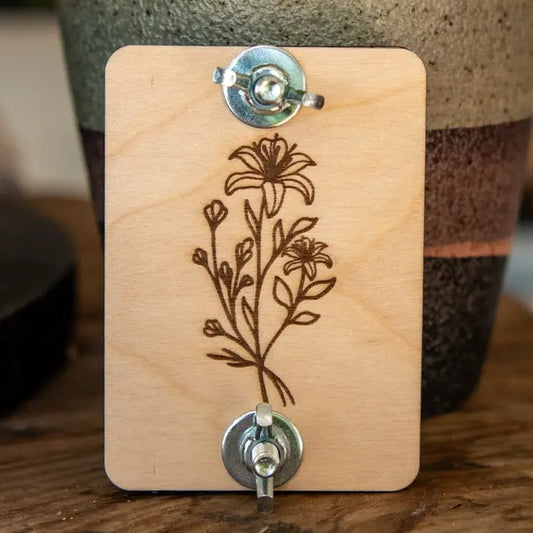 A small rectangular board with a flower engraved in it and screws on top and bottom