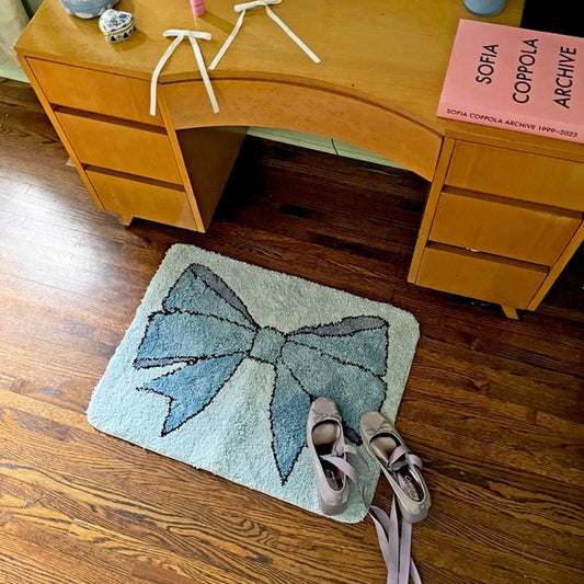 A light blue rectangular shag rug with a blue bow design.