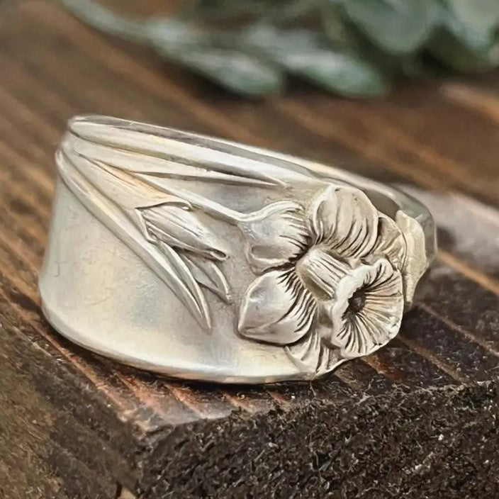 A thick silver ring with a daffodil engraved on it. 