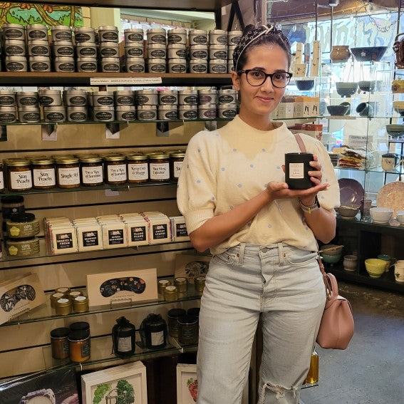 Artist of Starwick's Creations holding a candle she made in front of her display