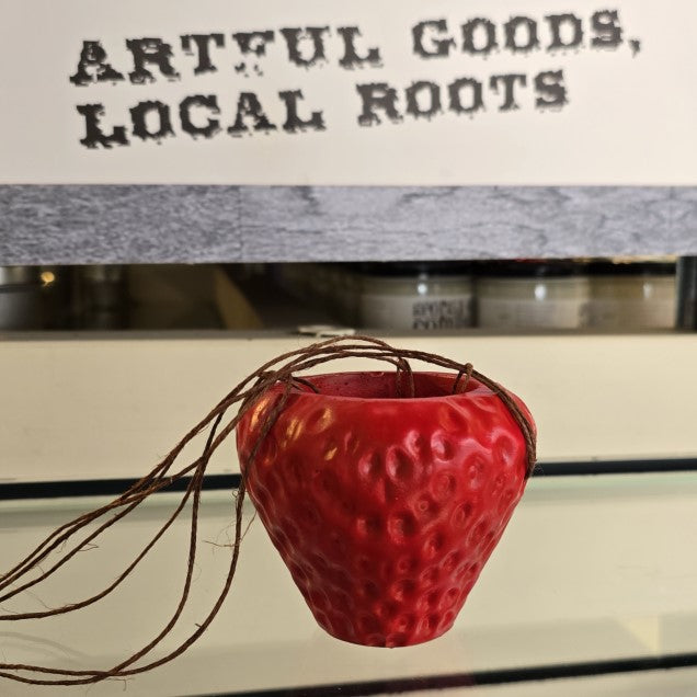 A small hanging planter shaped like a strawberry.