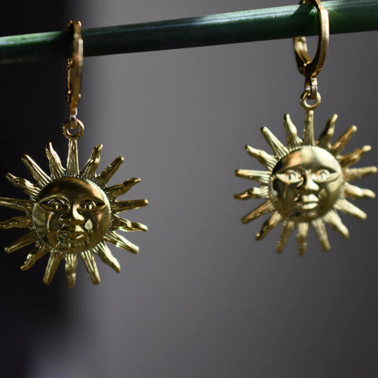 Gold huggie earrings shaped like suns with faces