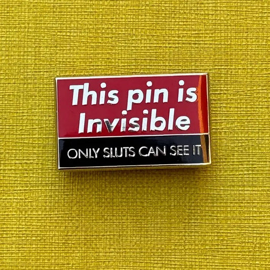 Red enamel pin with text that reads "This pin is invisible. Only sluts can see it"
