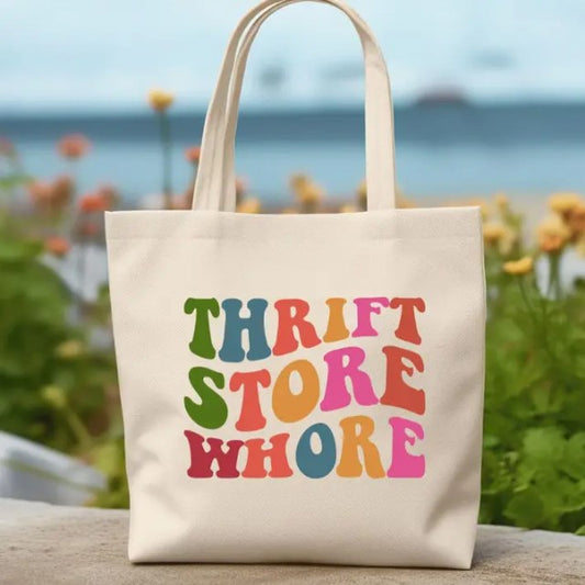 A tote bag featuring the words "Thrift Store Whore" in a wavy and colorful font.