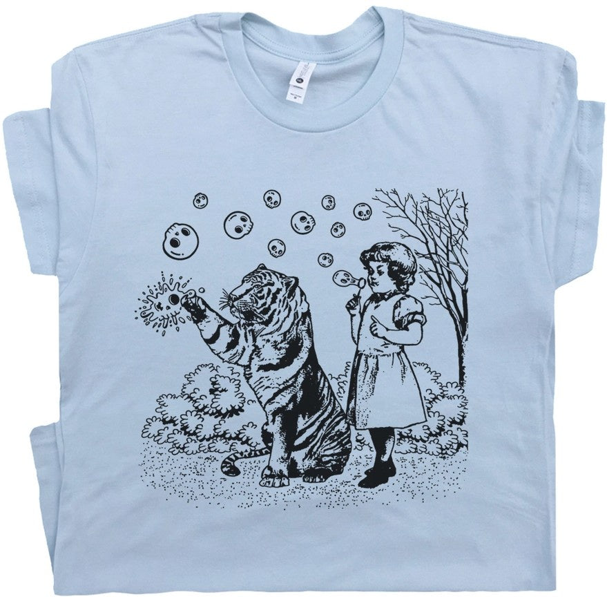 Light blue t-shirt with a graphic of a little girl blowing skull-shaped bubbles and a tiger popping them