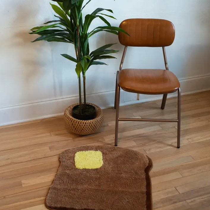 Small rug shaped like a piece of toast with a yellow pat of butter on it.