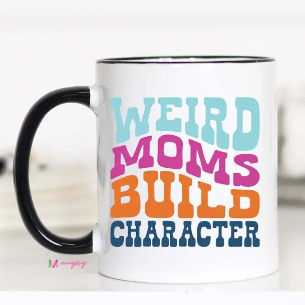 A white mug that reads "Weird Moms Build Character" in a wavy blue, pink and orange font.