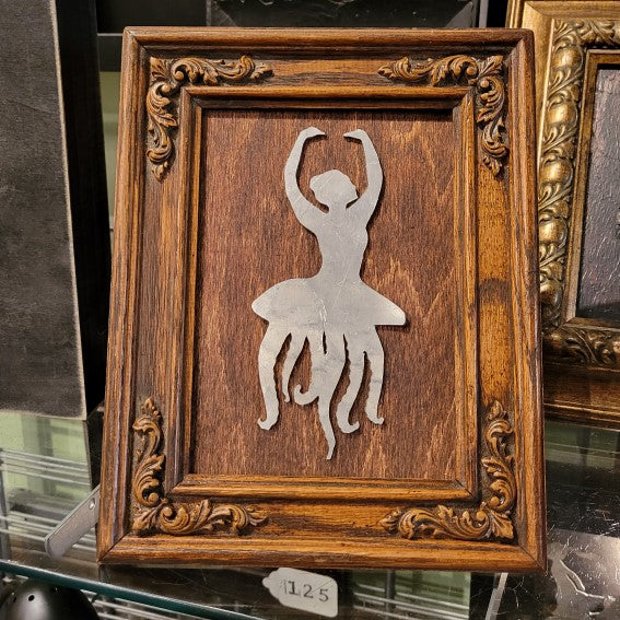Framed wood art featuring a ballerina octupus made from silver materials