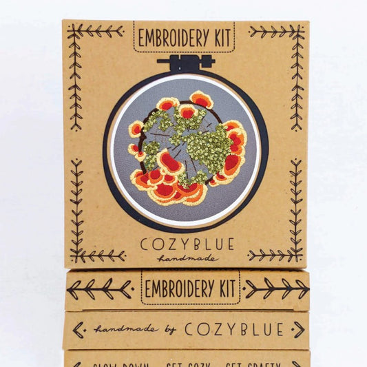 Embroidery kit with a design depicting wildflowers and fungus on a gray background
